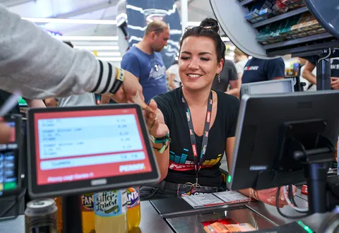 Eine Auszubildende sitzt an der Kasse in einem Festival Store