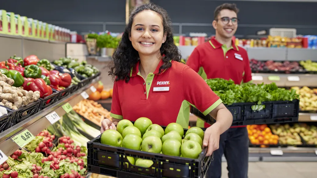 Eine PENNY Mitarbeiterin und ein Mitarbeiter befüllen die Obst und Gemüse Abteilung im Markt