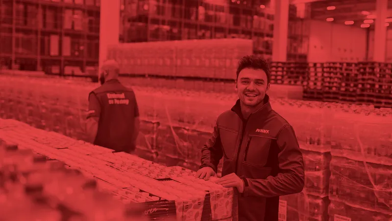 Ein lächelnder PENNY Mitarbeiter in einem Logistikstandort