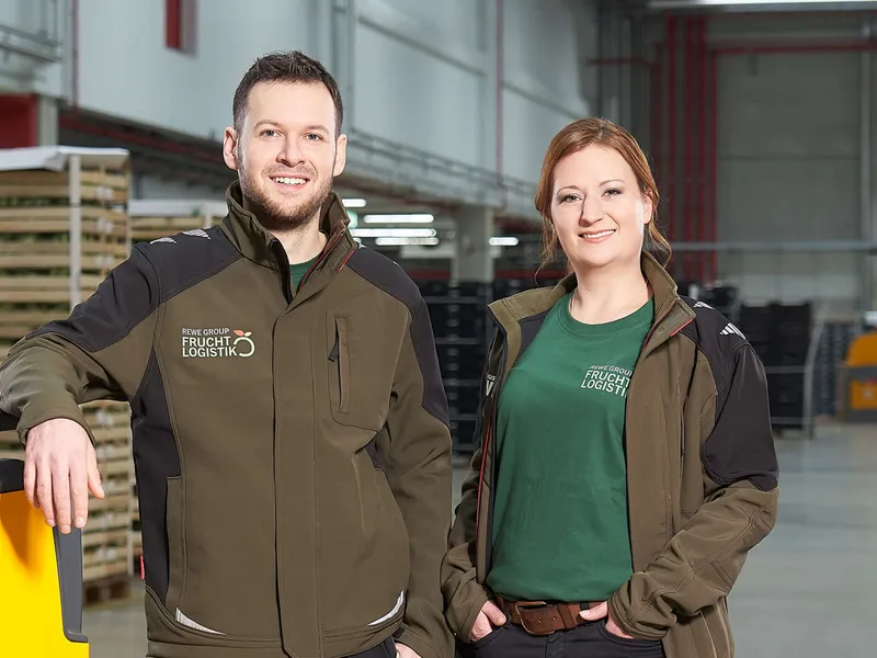 Zwei Mitarbeiter stehen im Lager, beide Tragen Fruchtlogistik Jacken